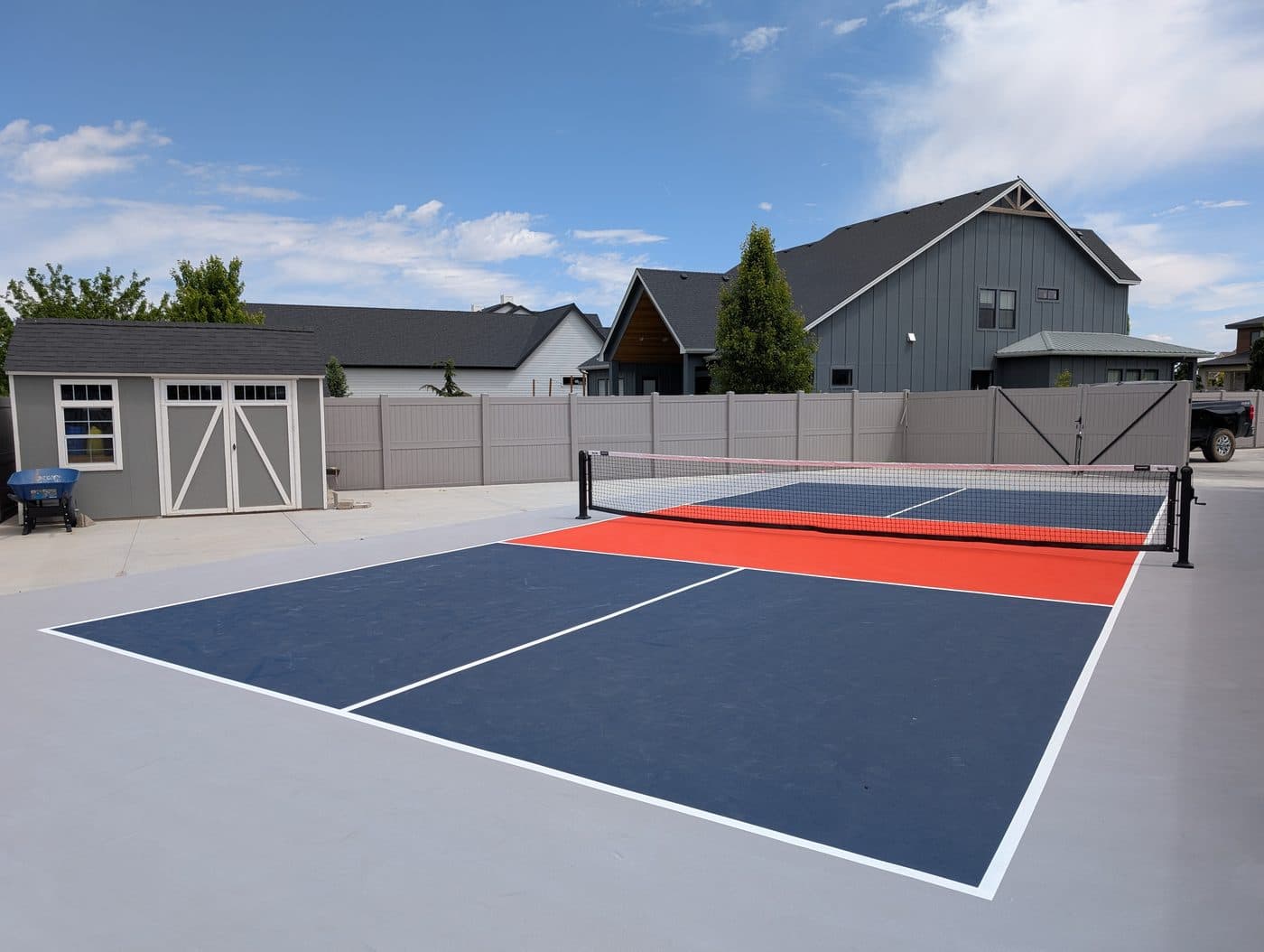 A finished navy and orange backyard pickleball court built by Idaho Custom Courts